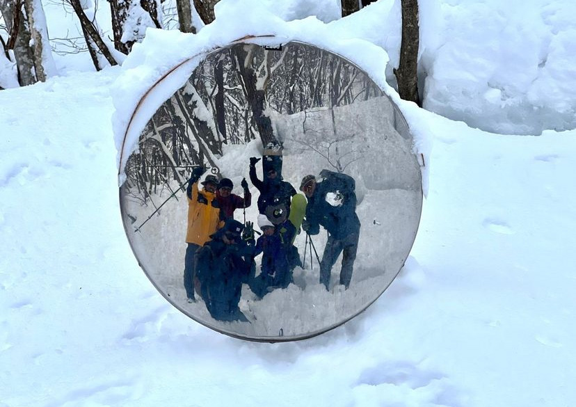 雪原の中、ミラー越しに写真に映る楽しげなツアー客
